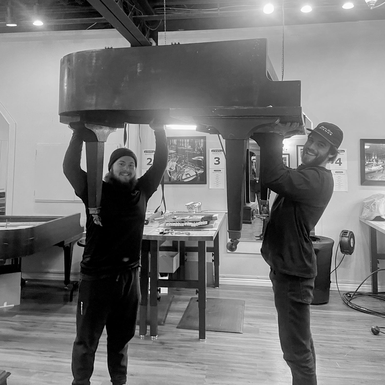 Brigham Larson Pianos piano moving team lifting a heavy grand piano in the family heirloom piano restoration shop.