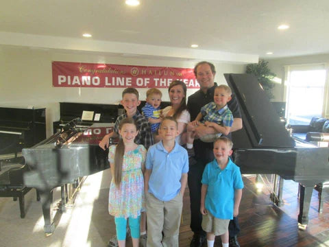 Larson Family posing in the first Brigham Larson Pianos music store with pianos in the background