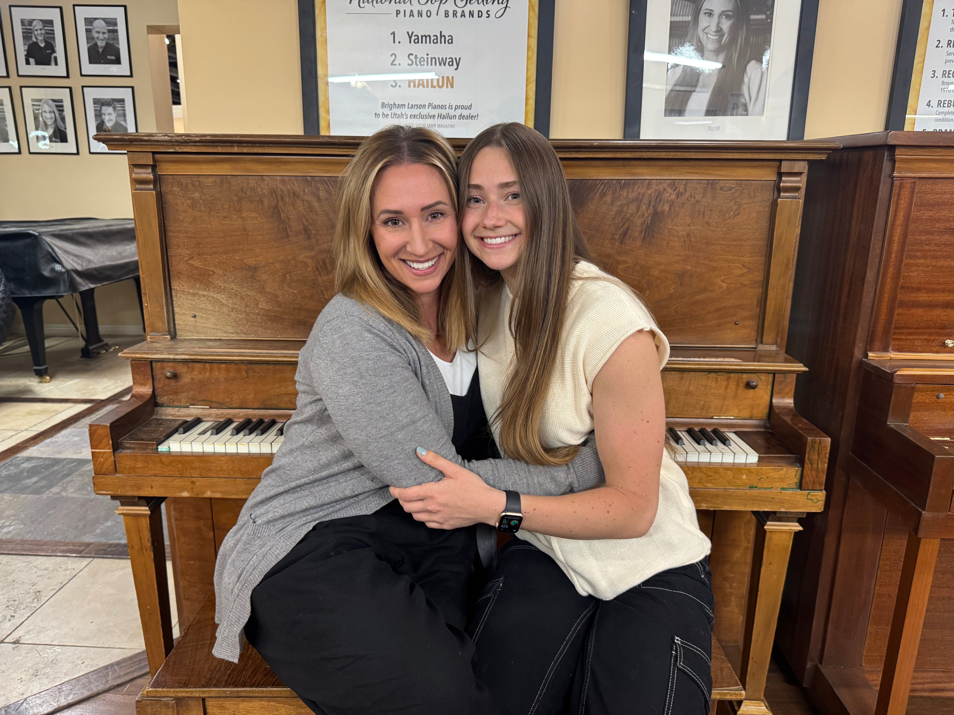 Special heirloom piano restoration "before" restoration. Owner of Brigham Larson Pianos, Karmel, and daughter sitting in front of the Larson heirloom Andrew Kohler. Fifth-generation family members posing with an antique upright heirloom piano being celebrated at Brigham Larson Pianos in Orem, UT.