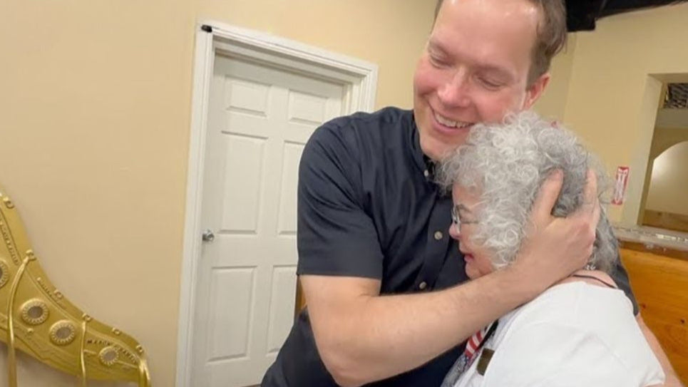 Load video: Brigham Larson hugging happy customer unveiling fully rebuilt family heirloom Schubert upright after piano restoration, rebuild, refinishing to happy family for the first time.